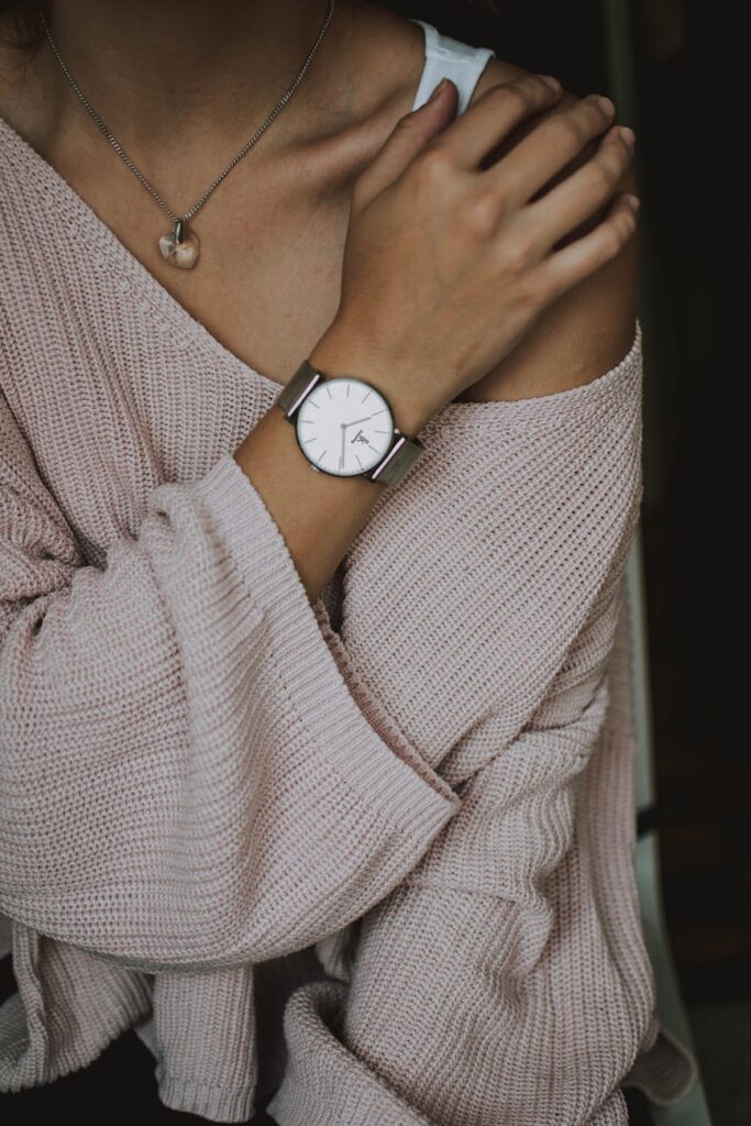 Chic fashion portrait of woman in cozy sweater showcasing stylish watch and necklace.