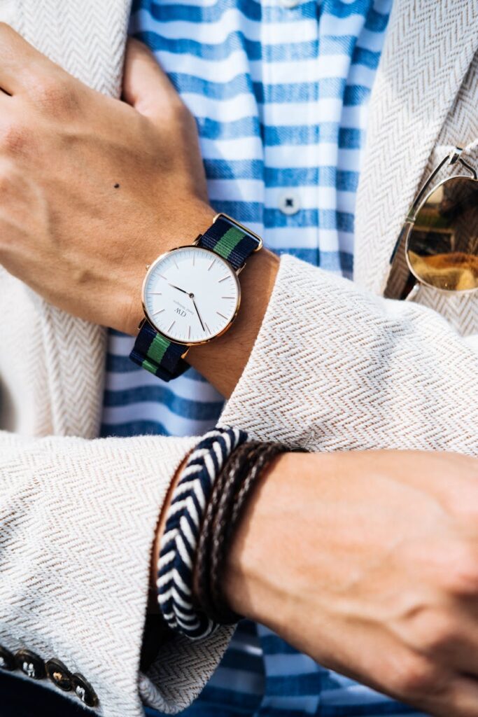 Close-up of a fashionable man's wrist showcasing a striped watch and bracelets.